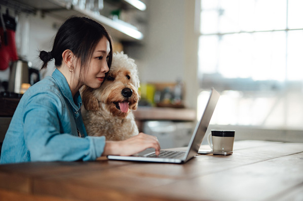 Frau mit Hund am Laptop zuhause arbeitet mit HTML5