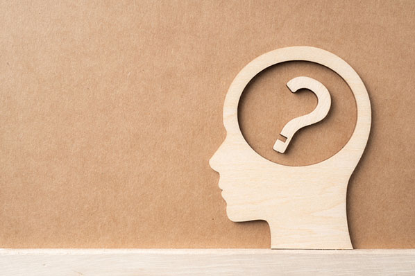 Kopf aus Holz mit Fragezeichen verdeutlicht kognitive Dissonanz