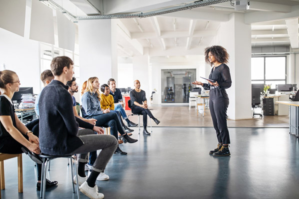 Frau moderiert Meeting mittels Moderationstechniken großer Gruppe im Büro