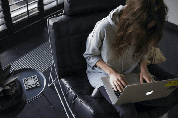 Frau sitzt mit Laptop auf einem Stuhl und nutzt ein Peer-to-Peer-Netzwerk