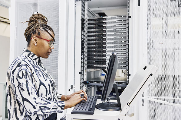 Frau im Serverraum am Laptop führt Reverse Engineering in Software durch