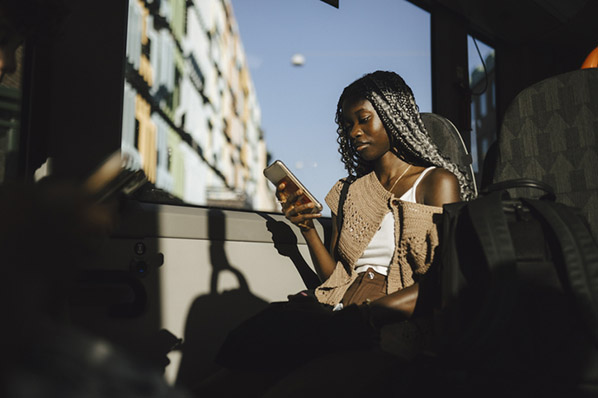 Frau im Bus schaut auf Handy wegen ständiger Erreichbarkeit
