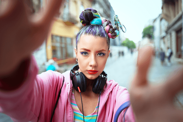 Frau mit bunten Haaren und Kleidung vor Kamera macht TikTok-Werbung